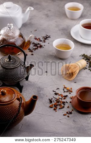 Tea Card. Variety Of Teapots And Cups On A Gray Background And Different Varieties Of Tea. Tea Still