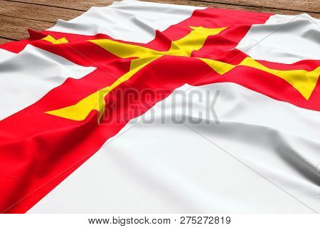Flag Of Guernsey On A Wooden Desk Background. Silk Guerns Flag Top View.