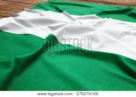 Flag Of Nigeria On A Wooden Desk Background. Silk Nigerian Flag Top View.