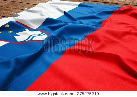 Flag Of Slovenia On A Wooden Desk Background. Silk Slovene Flag Top View.