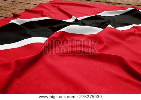 Flag Of Trinidad And Tobago On A Wooden Desk Background. Silk Trinidadian Flag Top View.