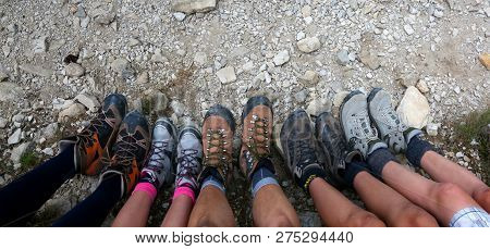 Legs And Boots Of A Family Of 5 With 3 Children Resting After The Hike In The Mountains