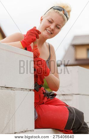 Woman Leveling Airbricks On Construction Site