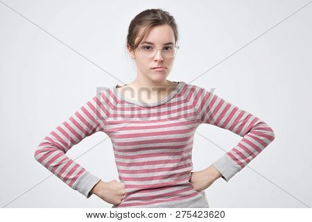 Unpleasant Young Lady In Pulover Holding Hands On Hips.