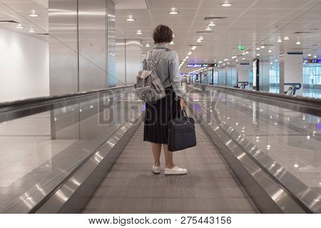 The Girl Is Riding On The Travolator At The Airport With A Laptop. Toned