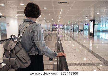 The Girl Is Riding On The Travolator At The Airport With A Laptop. Toned