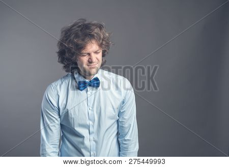 Portrait Of Exhausted Sad Guy With Shaggy Hair Standing And Looking Down With Apathy. Isolated On Gr