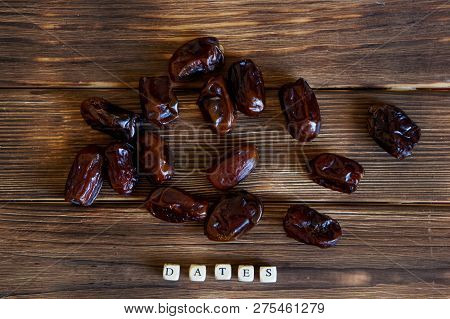 Dried Dates Lie On A Wooden Table. Explanatory Inscription. View From Above. High-calorie Foods.
