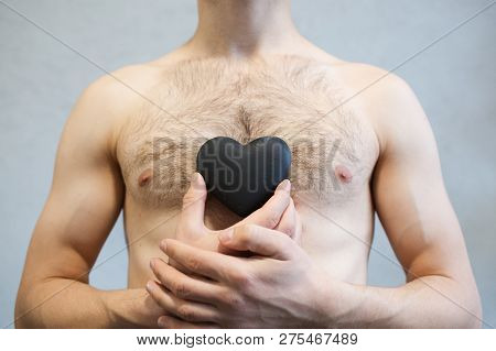 Portrait Of Black Heart In Man Hands, On Body Torso Background.