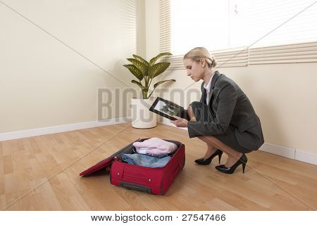 Podnikatelka při přípravě svého zavazadla businesstrip při pohledu na rodinný portrét