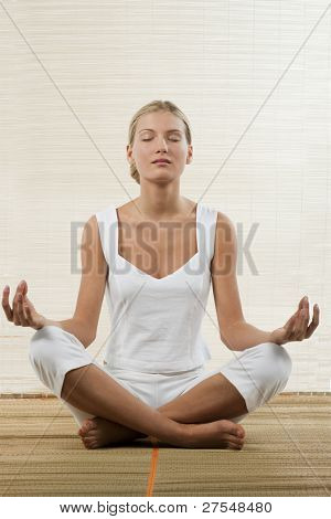 Ung kvinde siddende i lotus stilling og meditere