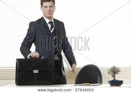 Businessman in his office with briefcase