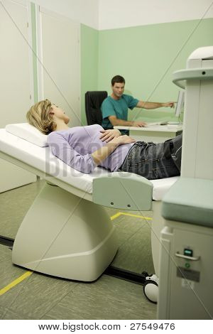 Mladá žena, obdrží magnetickou rezonancí na noze, zatímco doktor kontrola výsledků na monitoru