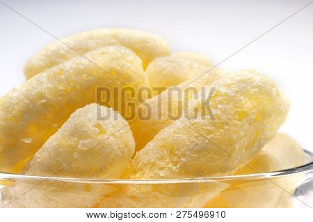 Yellow Corn Puffs In A Glass Bowl. Crunchy Flavored Puffed Snacks. Party, Movie, Tv, Game Snacks.