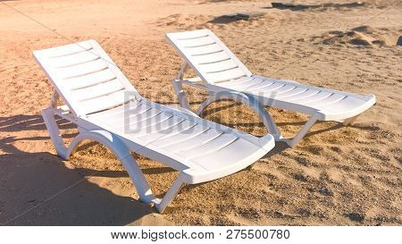 Two Sunlongers On The Sand Beach In Summer.