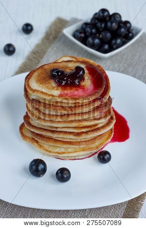 Stack Of American Pancakes With Blackcurrant Jam And Fresh Blackcurrant Berries Are Lying On A White