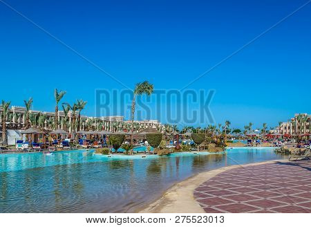 View Of The Hotel’s Recreation Area On The Beach And The Sea Shore, Palm Trees Under The Blue Sky Of