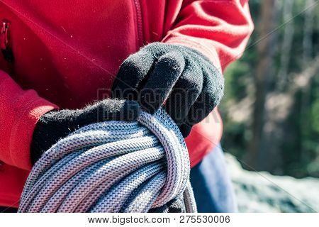 Close-up Of A Coiled Blue Climbing Rope In The Hands Of A Climber Male