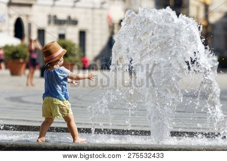 GENOA, ITALY - AUGUST 6, 2018: Girl bathing in fountain on Piazza de Ferrari during summer heat. Piazza De Ferrari is renowned for its fountain, which was restored in recent years