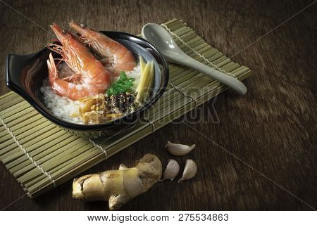 Rice Gruel Mixed With Prawn And Ginger, Scallion Slice And Deep Fried Garlic And Black Pepper In Bla