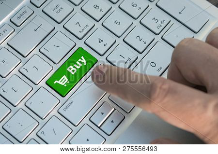 Buy Button On Computer Keyboard Showing Business Concept. A Male Finger Presses A Color Button On A 