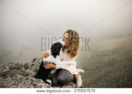 Dog Border Collie Lick Cool Girl On Edge Of Rock In Fog