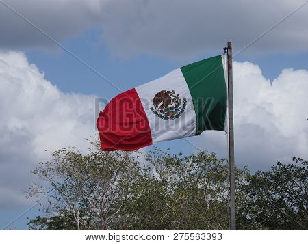 National Maxican Flag At Chichen Itza City Near Archaeological Site In Mexico With Trees And Cloudy 