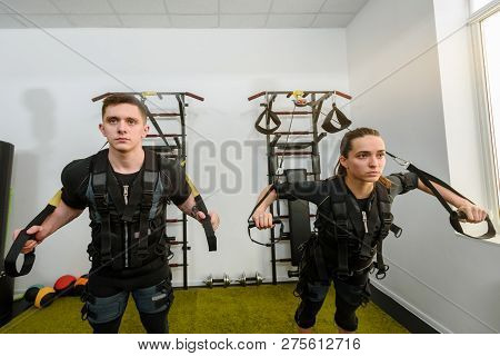 Man And Woman In Ems Suits Doing Suspension Training