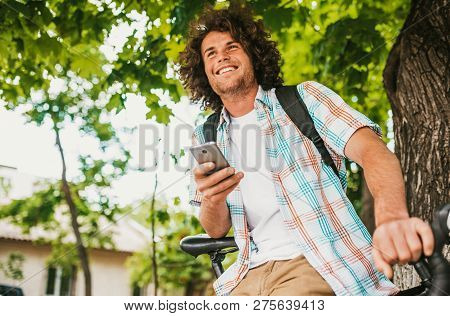 Bottom View Of Happy Young Male Student Smiling With Curly Hair Wearing Shirt With Backpack, Sitting