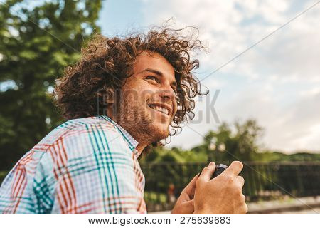 Horiontal Closeup Portrait Of Young Male With Curly Hair Checking Photos In His Digital Camera. Youn