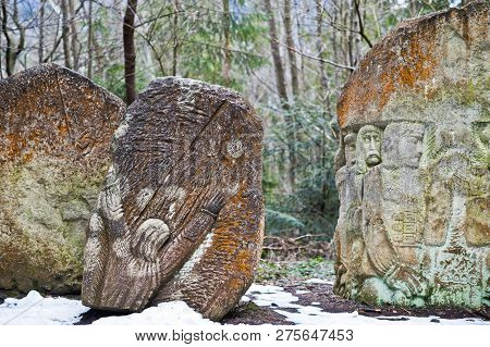 Ancient Large Stones With Engraving At Green Forest With Little Snow Cover In Carpathians Mountains.