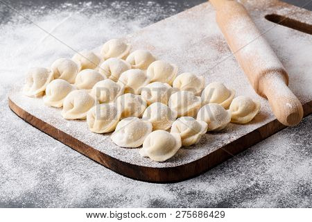 Uncooked Russian Pelmeni On Cutting Board And Ingredients For Homemade Pelmeni On White Table. Proce