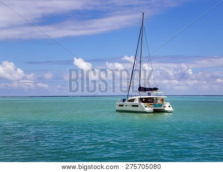 Lonely Catamaran In A Beautiful Turquoise Lagoon Near The Island Bora Bora In The Leeward Group Of T