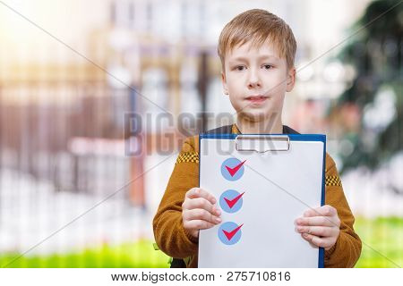 A Schoolboy Is Standing At Educational Establishment Blurred Background And Showing A Plane Table Wi