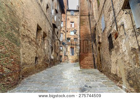 Medieval Narrow Street Vicolo Del Tone In Old City Siena, Tuscany, Italy.