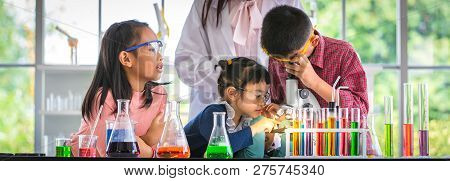 Science Teacher Teach Asian Students In Laboratory Room, Boy  Look Through Microscope, Colorful Test