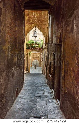 Medieval Narrow Street Vicolo Delle Scotte In Old City Siena. Tuscany, Italy.