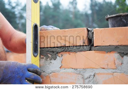 Bricklayer Measure Brick Wall With Spirit Level. Bricklaying New House Wall