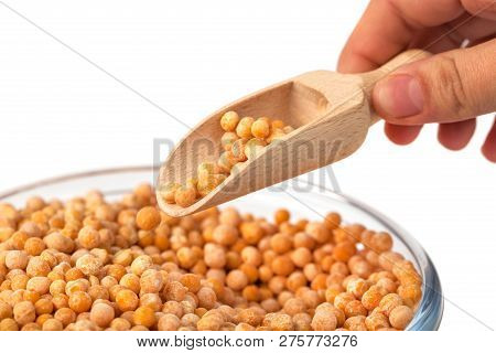 Spoon In Hand With Yellow Peas On White Background. Peas In Glass Bowl