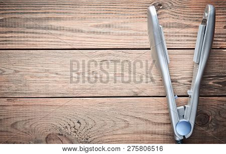 Iron For Leveling Hair On A Wooden Table. Hair Straighteners. Copy Space. Top View.