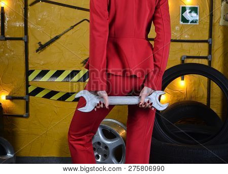 Stylish Mechanic Girl In Trendy Clothes Is Holding A Wrench On The Background Of The Workshop Of An 