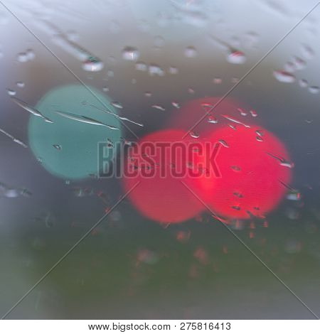 Abstract Pattern Of Colorful Lights And Rain Drops During Downpour On Winshield Of Car After Dark