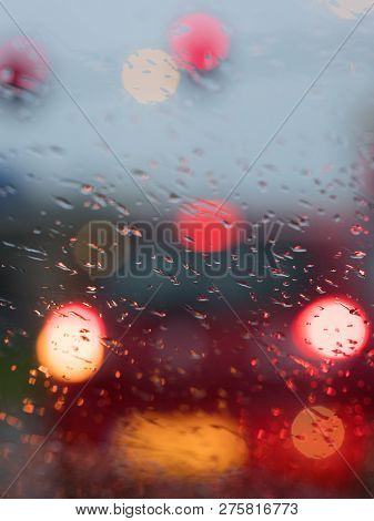 Abstract Pattern Of Colorful Lights And Rain Drops During Downpour On Winshield Of Car After Dark