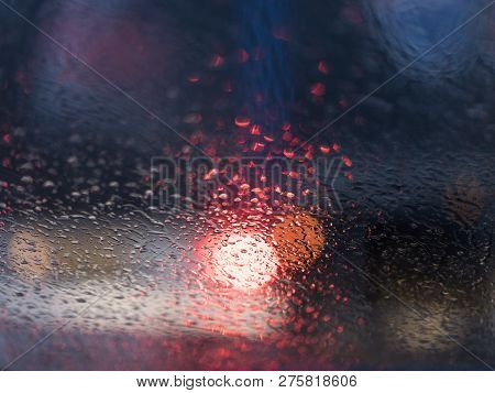 Abstract Pattern Of Colorful Lights And Rain Drops During Downpour On Winshield Of Car After Dark