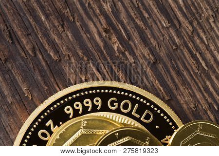 A Few Gold Coins Fineness 999.9 On A Background Of Rough Wood Texture.