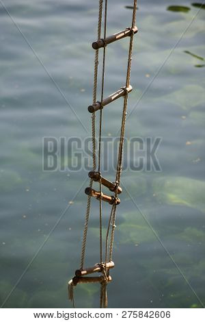 Achieving Success. Rope Ladder. Jacobs Ladder. Rope Ladder With Wooden Steps. Rope Over Water Surfac