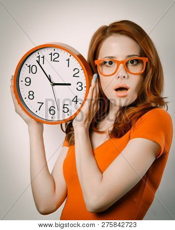 Surprised Redhead Girl With Huge Alarm Clock On Light Background.