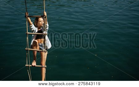 The Highest Ambition. Sensual Woman Hang On Rope Over Water Surface. Pretty Woman Climb Jacobs Ladde