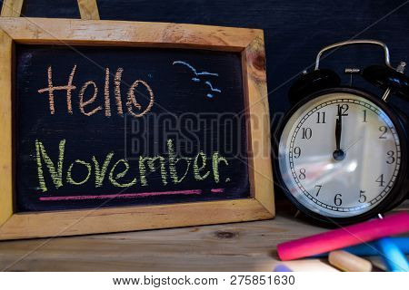 Hello November. Back To School Concept. Alarm Clock On Wooden With Blackboard On Background