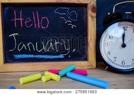 Hello January. Back To School Concept. Alarm Clock On Wooden With Blackboard On Background